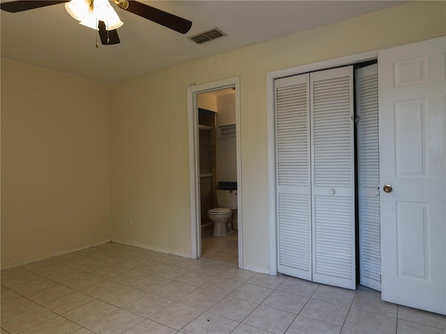 unfurnished bedroom with ceiling fan, ensuite bathroom, a closet, and light tile patterned flooring