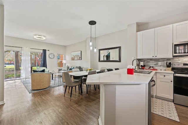 kitchen featuring pendant lighting, dark wood-type flooring, white cabinets, sink, and appliances with stainless steel finishes