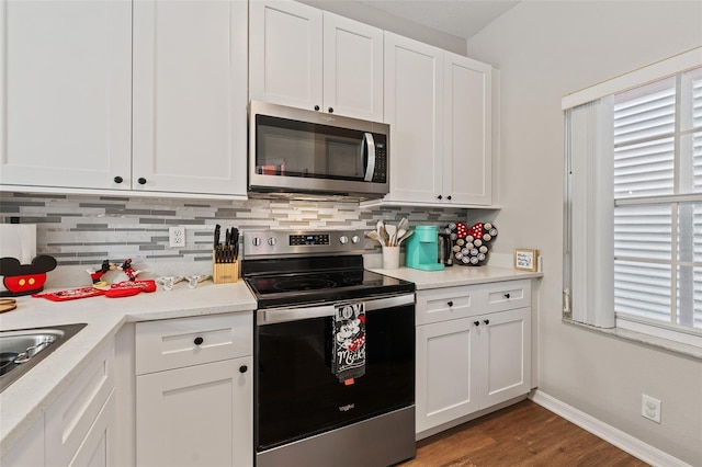 kitchen featuring decorative backsplash, white cabinetry, stainless steel appliances, and hardwood / wood-style flooring