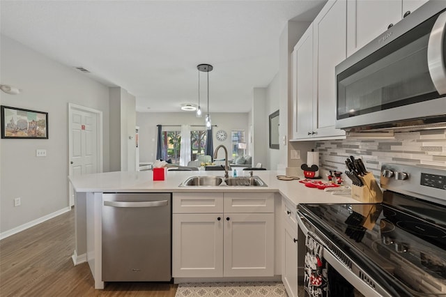 kitchen featuring kitchen peninsula, appliances with stainless steel finishes, light wood-type flooring, sink, and white cabinetry