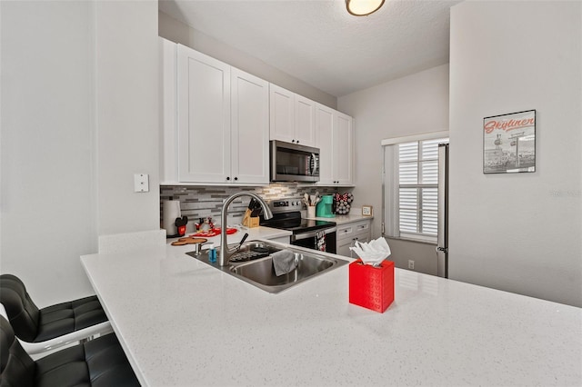 kitchen featuring white cabinetry, sink, tasteful backsplash, a textured ceiling, and appliances with stainless steel finishes