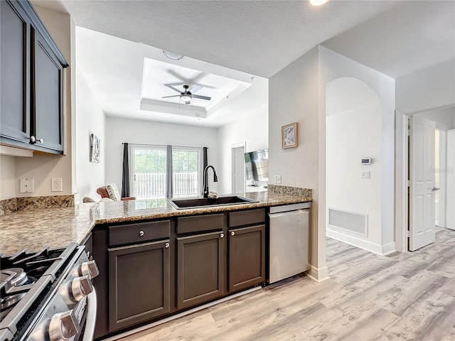 kitchen with stainless steel appliances, a peninsula, a sink, visible vents, and a raised ceiling