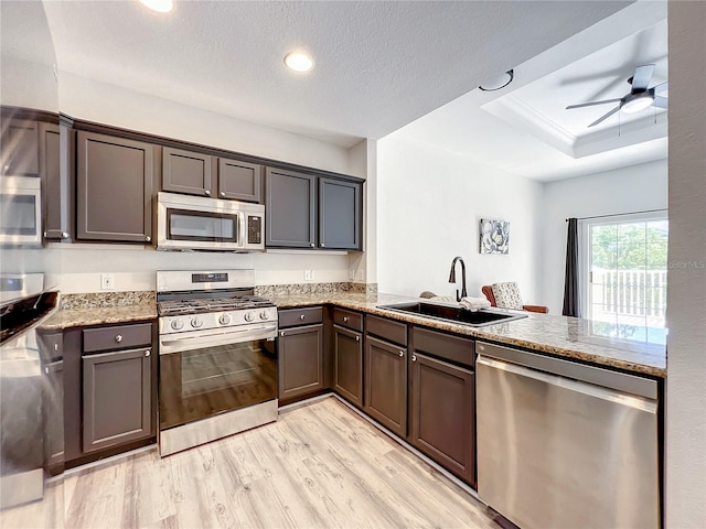 kitchen featuring sink, light stone countertops, light wood-type flooring, appliances with stainless steel finishes, and kitchen peninsula