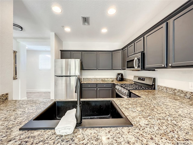 kitchen with gray cabinets, light stone countertops, sink, and appliances with stainless steel finishes