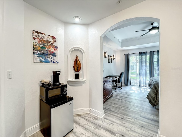 corridor featuring light hardwood / wood-style floors and a tray ceiling