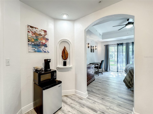 7510 Seven Eagles Way Unit 7510, Reunion, FL 34747 - hallway featuring arched walkways, light wood-style floors, baseboards, a tray ceiling, and an office area