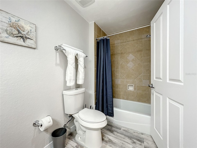 bathroom featuring toilet, visible vents, shower / bath combo with shower curtain, and wood finished floors