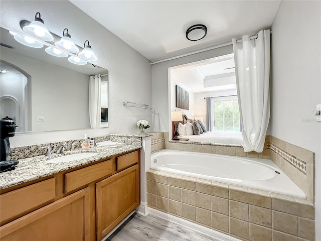 full bathroom with a garden tub, vanity, and wood finished floors