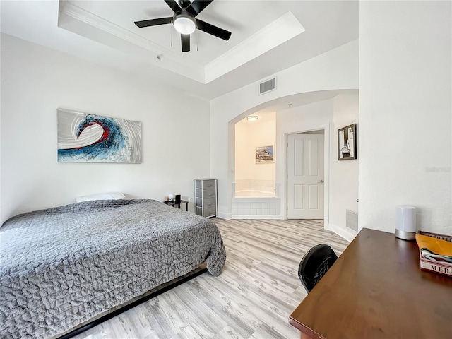 bedroom with hardwood / wood-style flooring, crown molding, ceiling fan, and a tray ceiling