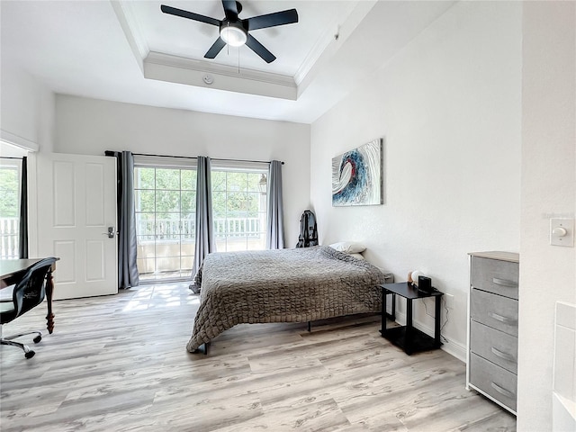 bedroom with ceiling fan, light wood-type flooring, a tray ceiling, and multiple windows