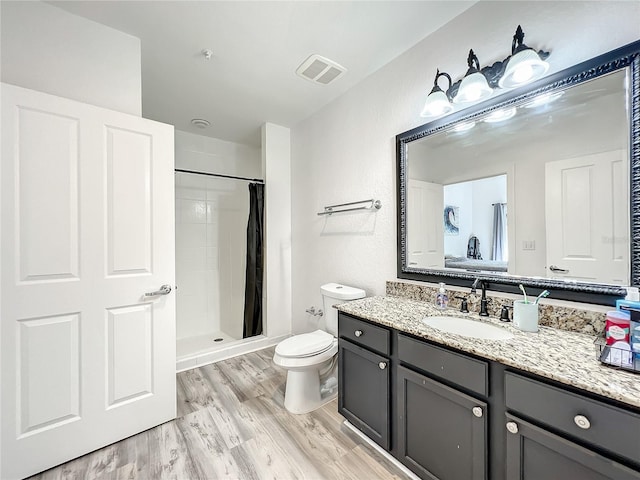 bathroom with vanity, toilet, wood-type flooring, and walk in shower