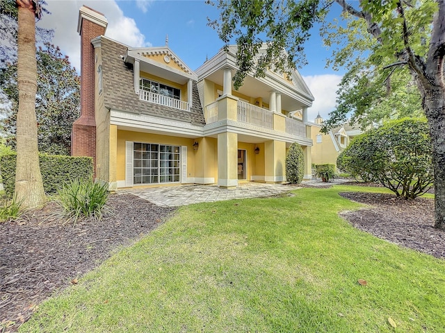 back of property with a patio, a balcony, a shingled roof, a yard, and stucco siding