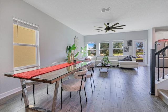 dining space with a textured ceiling, ceiling fan, and dark wood-type flooring