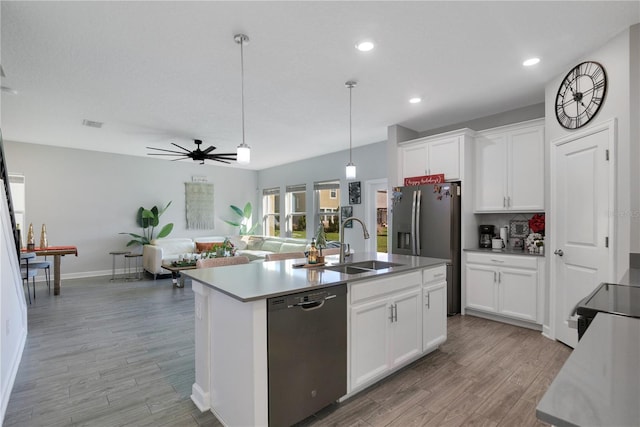 kitchen with white cabinets, sink, stainless steel appliances, and a kitchen island with sink