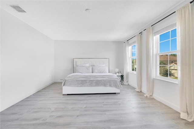 bedroom with light wood-type flooring and a textured ceiling