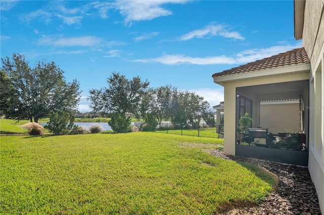 view of yard featuring a sunroom and a water view