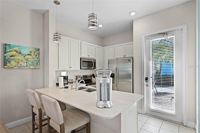 kitchen featuring kitchen peninsula, appliances with stainless steel finishes, pendant lighting, white cabinets, and light tile patterned flooring