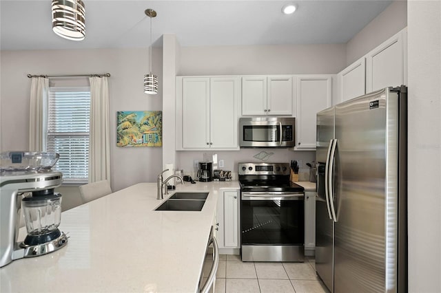 kitchen with stainless steel appliances, sink, light tile patterned floors, white cabinetry, and hanging light fixtures