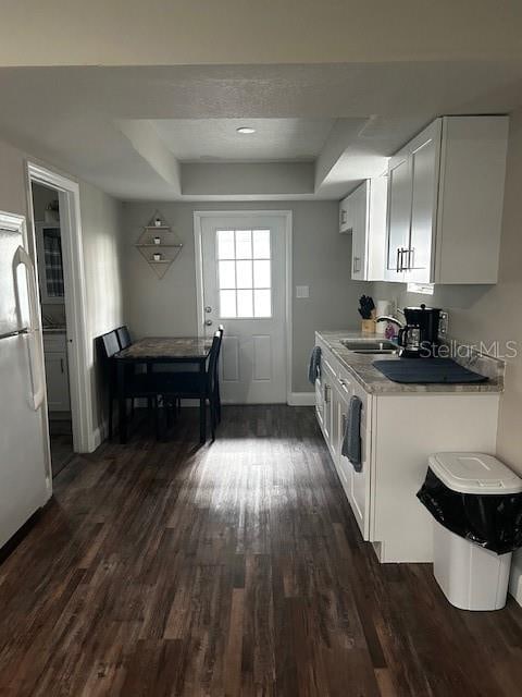 kitchen featuring dark hardwood / wood-style flooring, a tray ceiling, sink, white refrigerator, and white cabinetry