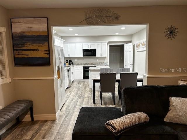 kitchen featuring white cabinets, light wood-type flooring, and black appliances