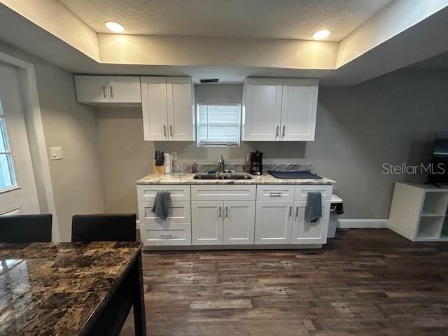 kitchen featuring white cabinetry, sink, and light stone counters