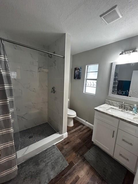 bathroom featuring hardwood / wood-style floors, vanity, a shower with curtain, toilet, and a textured ceiling