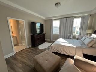 bedroom featuring ensuite bath and dark wood-type flooring