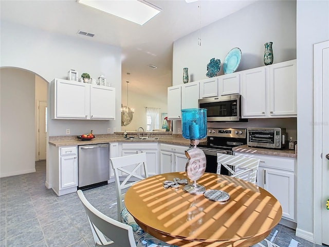 kitchen featuring sink, white cabinets, hanging light fixtures, and appliances with stainless steel finishes