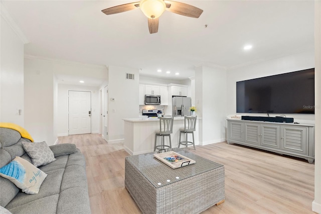 living room with light hardwood / wood-style flooring, ceiling fan, and ornamental molding