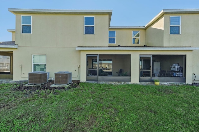 back of property featuring a sunroom, central AC, and a lawn