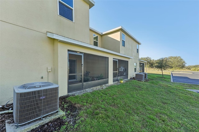 back of house featuring a lawn, a sunroom, and cooling unit