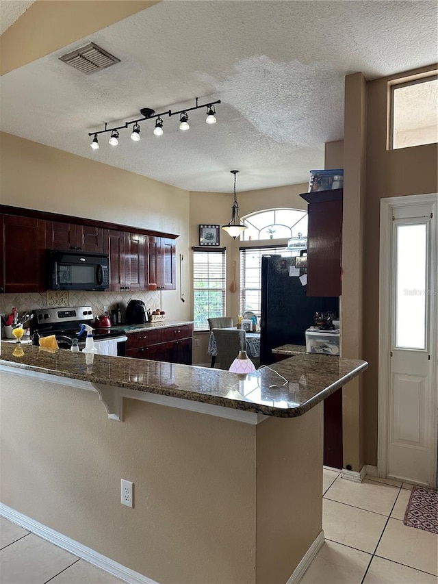 kitchen with kitchen peninsula, a textured ceiling, black appliances, light tile patterned floors, and decorative light fixtures