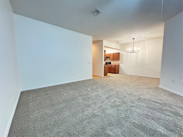 unfurnished room featuring a chandelier, carpet, and a textured ceiling