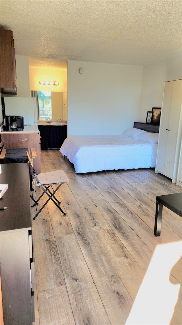 bedroom with a textured ceiling and light hardwood / wood-style flooring