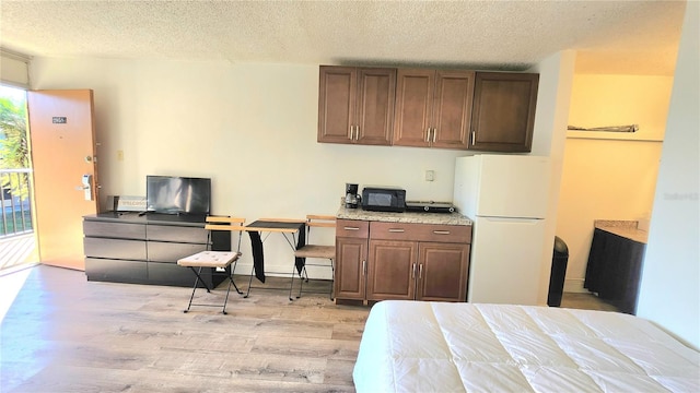 bedroom featuring access to exterior, white fridge, a textured ceiling, and light wood-type flooring