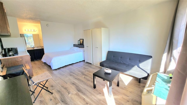 bedroom with light wood-type flooring and a textured ceiling