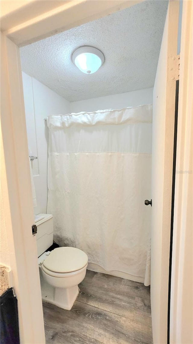 bathroom with wood-type flooring, a textured ceiling, and toilet