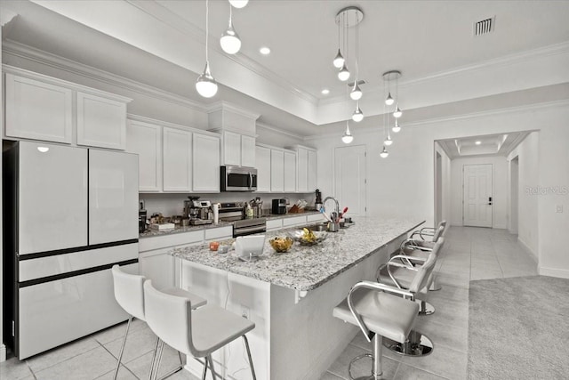 kitchen with a kitchen breakfast bar, an island with sink, decorative light fixtures, white cabinetry, and stainless steel appliances