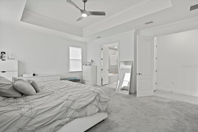 carpeted bedroom featuring a tray ceiling, ensuite bath, ceiling fan, and ornamental molding