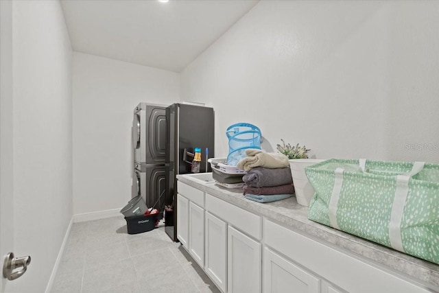 laundry room featuring stacked washer / drying machine and light tile patterned floors