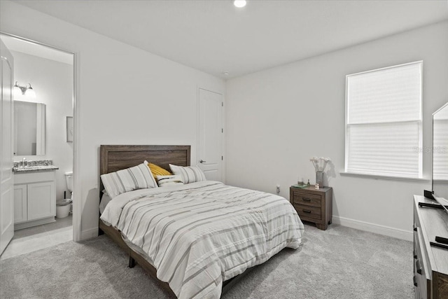 bedroom featuring connected bathroom, light carpet, and sink