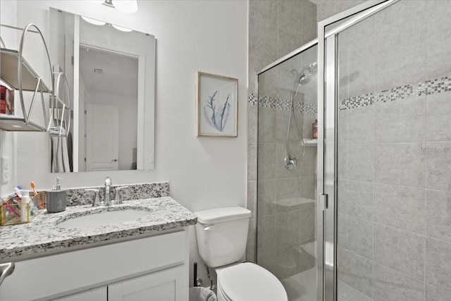 bathroom featuring vanity, an enclosed shower, and toilet