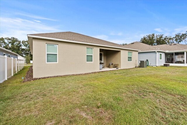 rear view of property featuring a lawn and central AC