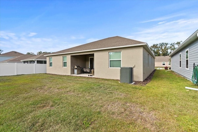 rear view of house featuring a patio, central air condition unit, and a lawn