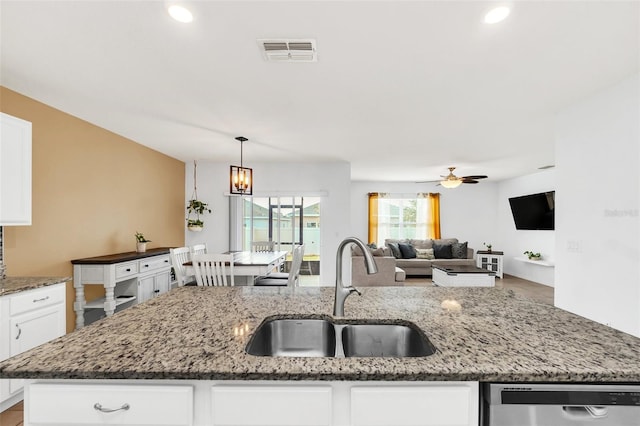 kitchen with dishwasher, ceiling fan with notable chandelier, dark stone counters, and sink