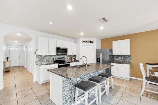 kitchen with white cabinets, appliances with stainless steel finishes, an island with sink, and sink