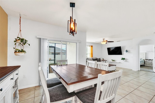 tiled dining space with ceiling fan with notable chandelier