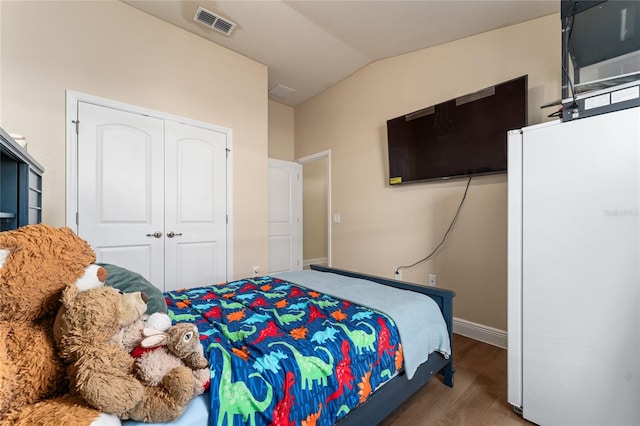 bedroom with a closet, hardwood / wood-style floors, and vaulted ceiling