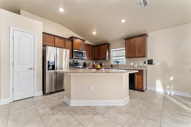 kitchen with a kitchen island, light tile patterned floors, appliances with stainless steel finishes, and vaulted ceiling