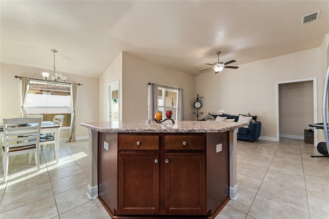 kitchen featuring pendant lighting, ceiling fan with notable chandelier, a center island with sink, and light tile patterned floors